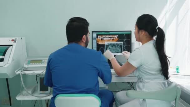 インド人とアジア人の歯科医が口腔と治療のパノラマ写真を議論 — ストック動画