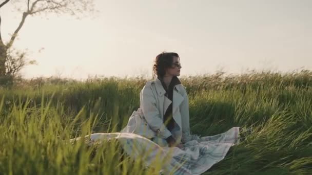 Handsome Girl Glasses Beige Trench Coat Sitting Picnic Blanket Green — Stock Video