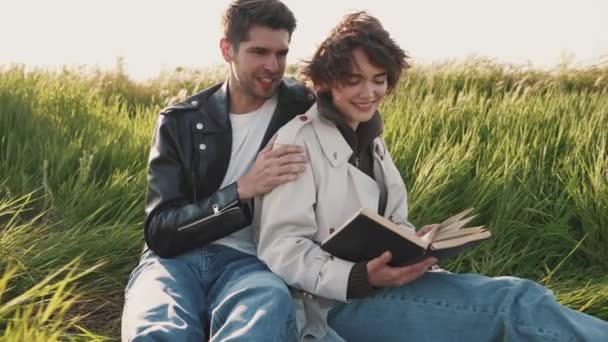 Cute Couple Reading Book Hugging While Sitting Picnic Blanket Field — Stock Video
