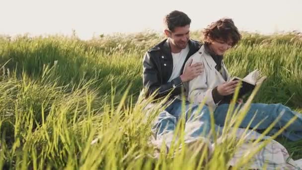 Smiling Couple Reading Book Hugging While Sitting Picnic Blanket Field — Stock Video