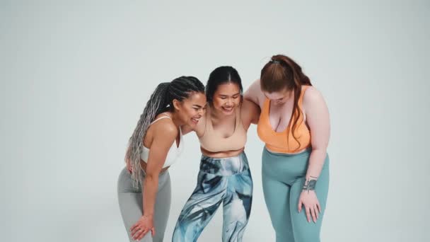 Tre Donne Multietniche Sorridenti Abbigliamento Sportivo Che Abbracciano Sfondo Grigio — Video Stock