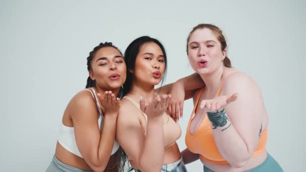 Три Положительные Многоэтнические Женщины Спортивной Одежде Обнимаются Дуют Воздушные Поцелуи — стоковое видео