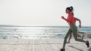 Şafakta deniz kenarında koşan çok uluslu ciddi bir çift.