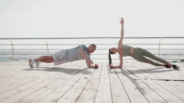 Mooi Multinationaal Paar Doen Plank Oefening Door Zee Bij Dageraad — Stockvideo