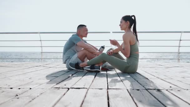 Positief Multinationaal Echtpaar Dat Praat Water Drinkt Het Sporten Zee — Stockvideo