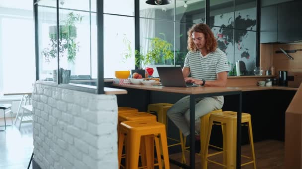 笑顔巻き毛の男で眼鏡作業上のラップトップでオフィスキッチン — ストック動画