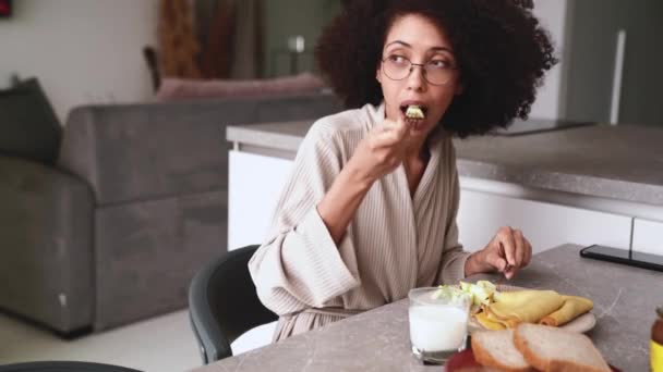 Ładna Afrykańska Kobieta Okularach Płaszczu Jedząc Śniadanie Naleśniki Jabłka Kuchni — Wideo stockowe