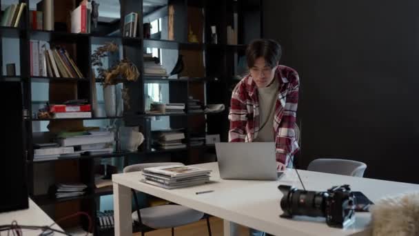 集中型アジア人男性で プレイシャツはノートパソコン上で作業スペースで動作します — ストック動画