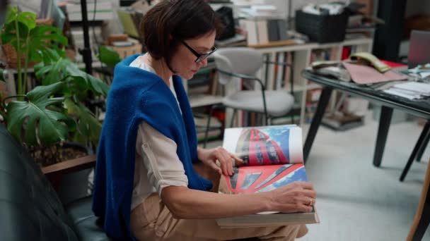 Concentrato Donna Matura Designer Occhiali Guardando Libro Archi Working Spazio — Video Stock
