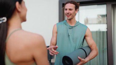 Confident couple of sportsmen talking before yoga practice at hotel outdoors