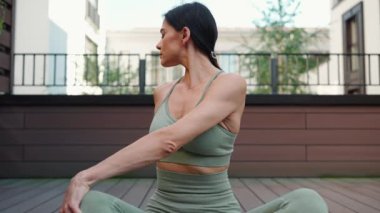 Focused brunette woman meditating on yoga mat with closed eyes on hotel balcony