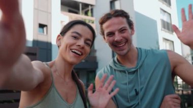 Pretty couple of sportsmen filming video on camera and talking before yoga practice at hotel outdoors