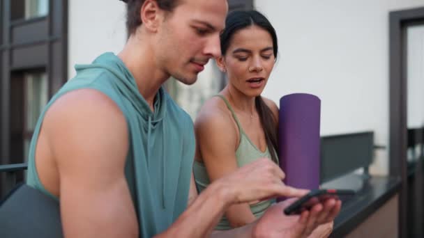 Positive Couple Sportsmen Talk Watch Video Cell Phone Yoga Practice — Stockvideo