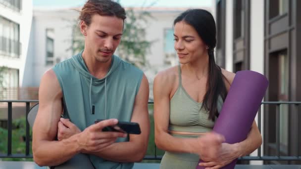 Smiling Couple Sportsmen Talk Watch Video Cell Phone Yoga Practice — Vídeo de Stock