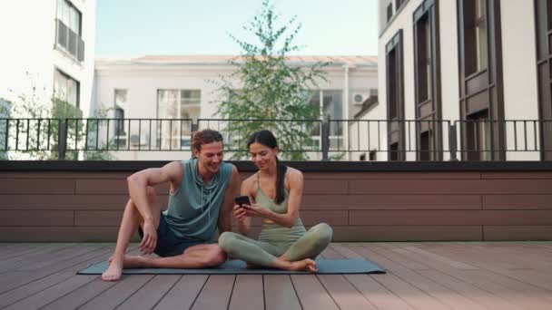 Funny Couple Sportsmen Talk Watch Video Cell Phone Yoga Practice — Vídeo de stock