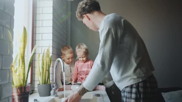 Blond Young Father Washes Dishes Talks His Children Who Watching — Stock Video