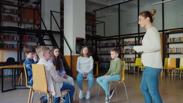 真剣な先生が学校の授業で椅子に座っている子供たちに話しかける — ストック動画