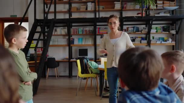 Przystojny Nauczyciel Wyjaśnia Dzieciom Zasady Gry Karty Siedząc Kółku Krzesłach — Wideo stockowe