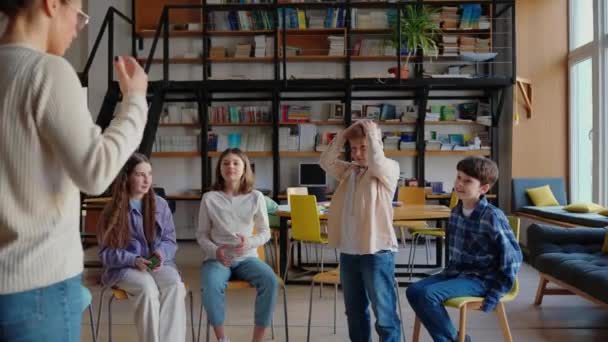 Meditatív Tanár Gesztus Játék Gyerekekkel Miközben Körben Székek Könyvtár Iskolában — Stock videók