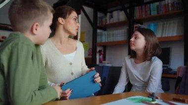 Meditasyon öğretmeni kütüphanedeki çizim masasında çocuklarla konuşuyor