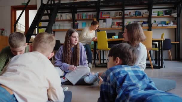 Töprengő Gyerekek Beszélgetnek Osztályban Miközben Körbe Ülnek Jegyzetfüzetbe Írnak Könyvtárban — Stock videók