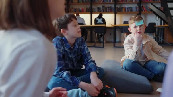 Skoncentrowane Dzieciaki Grają Zgadnij Kim Jestem Papierami Czole Siedząc Kółku — Wideo stockowe