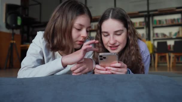 Okulda Kütüphanede Cep Telefonuyla Mesajlaşan Gülümseyen Genç Kızlar — Stok video