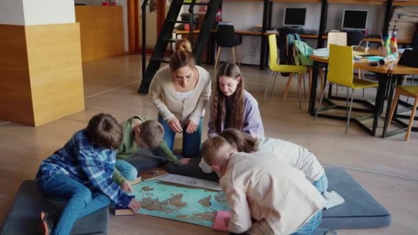 Pewne Siebie Dzieci Ich Nauczyciel Patrzą Mapę Świata Siedzącego Podłodze — Wideo stockowe