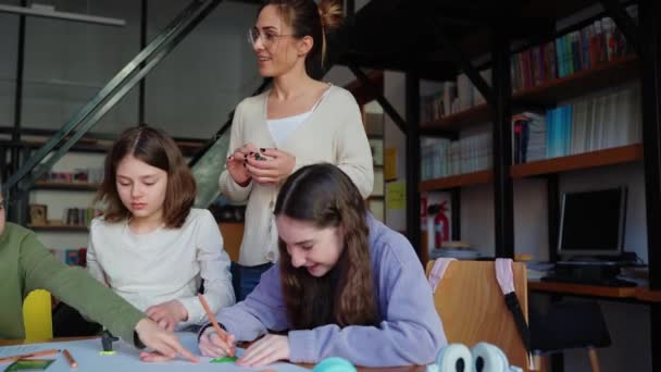 陽気な教師が図書館で子供たちとプラスチック製の図形を形成する — ストック動画