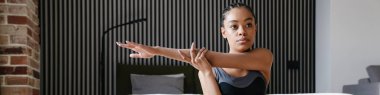 Attractive young healthy african woman doing yoga exercises on a fitness mat in the bedroom, yoga positions
