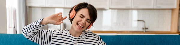 Szczęśliwa Piękna Dziewczyna Śpiewa Podczas Słuchania Muzyki Słuchawkami Kanapie Domu — Zdjęcie stockowe