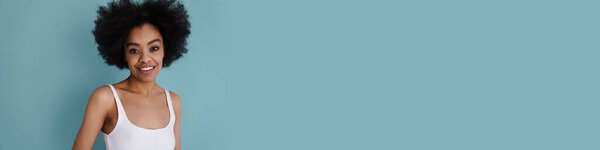 Счастливая африканская американская девушка улыбается и смотрит в камеру изолированы на синем фоне