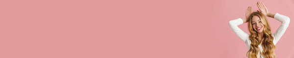 Красивая девушка с длинными волосами, стоящая на розовом фоне, позирует