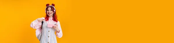 Radosna Dziewczyna Rudymi Włosami Słuchawkach Wskazując Palcem Komórkę Odizolowaną Żółtym — Zdjęcie stockowe