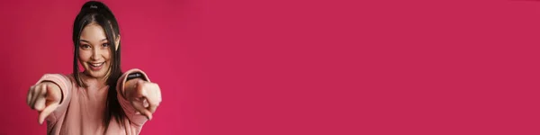 Азиатская Брюнетка Улыбается Указывает Пальцем Камеру Изолированную Над Фиолетовой Стеной — стоковое фото