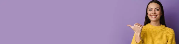Счастливая Милая Девушка Улыбается Показывая Пальцем Сторону Фиолетовом Фоне — стоковое фото