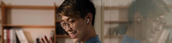 Sonriendo Asiático Chico Auriculares Ondeando Mano Mientras Que Hacer Videollamada —  Fotos de Stock