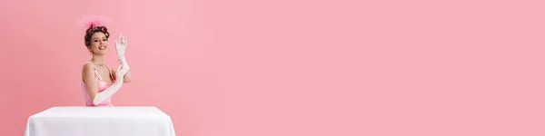 Молодая Женщина Перчатках Улыбается Камеру Сидя Столом Изолированы Розовом Фоне — стоковое фото