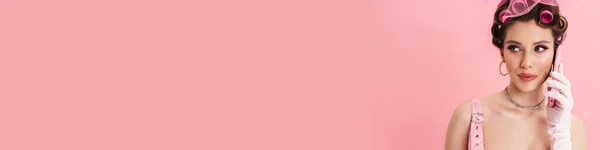Молодая Женщина Бигуди Говорить Смартфоне Глядя Сторону Изолированы Розовый Фон — стоковое фото