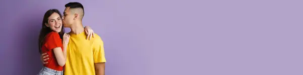 Брюнетка Счастливая Пара Обнимает Целует Камеру Изолированы Через Фиолетовую Стену — стоковое фото