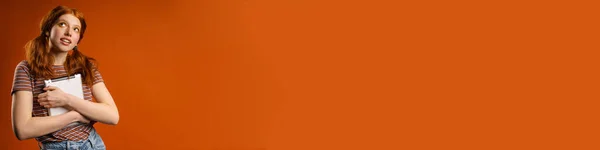 Imbir Kobieta Ogonami Patrząc Górę Podczas Pozowania Tabletem Wyizolowane Pomarańczowym — Zdjęcie stockowe