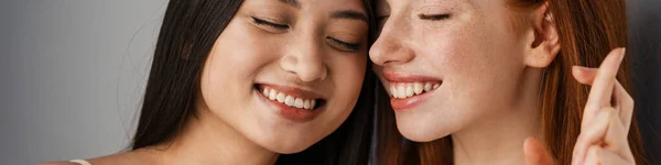 Dwie Uśmiechnięte Młode Wielonarodowe Kobiety Stojące Razem Nad Białą Ścianą — Zdjęcie stockowe