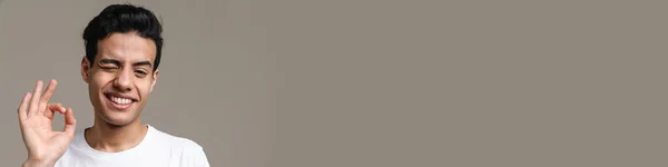 Brunetka Latynoski Mężczyzna Shirt Mruga Gestykuluje Przed Kamerą Odizolowany Szarym — Zdjęcie stockowe