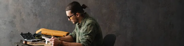 Artigiano Barbuto Focalizzato Annotare Note Mentre Lavora Con Pelle Officina — Foto Stock