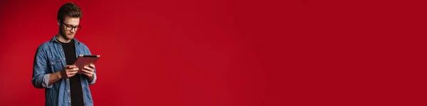 Спокойный Молодой Человек Повседневной Одежде Стоит Фоне Красной Стены Держа — стоковое фото
