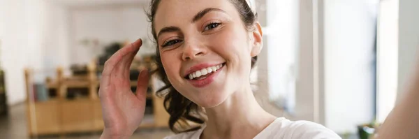 stock image Close up of a smiling young brunette woman casually dressed standing in the office, taking a selfie