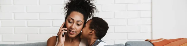 Mulher Sorridente Preta Falando Celular Enquanto Abraça Seu Filho Casa — Fotografia de Stock