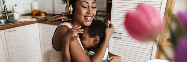 Mulher Feliz Preta Fones Ouvido Abraçando Seu Filho Enquanto Trabalhava — Fotografia de Stock
