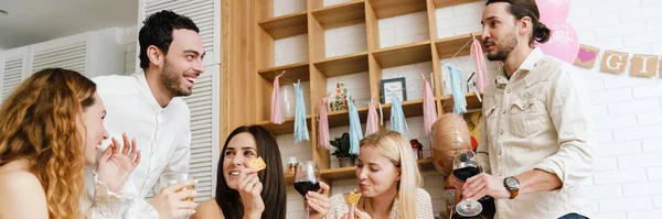 幸せな若い友人笑いと食べるスナック中に性別明らかにパーティー室内 — ストック写真