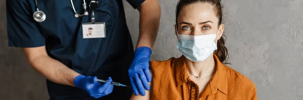 医療マスクの病気の女性は キャビネットに座ってワクチンショットを得る — ストック写真